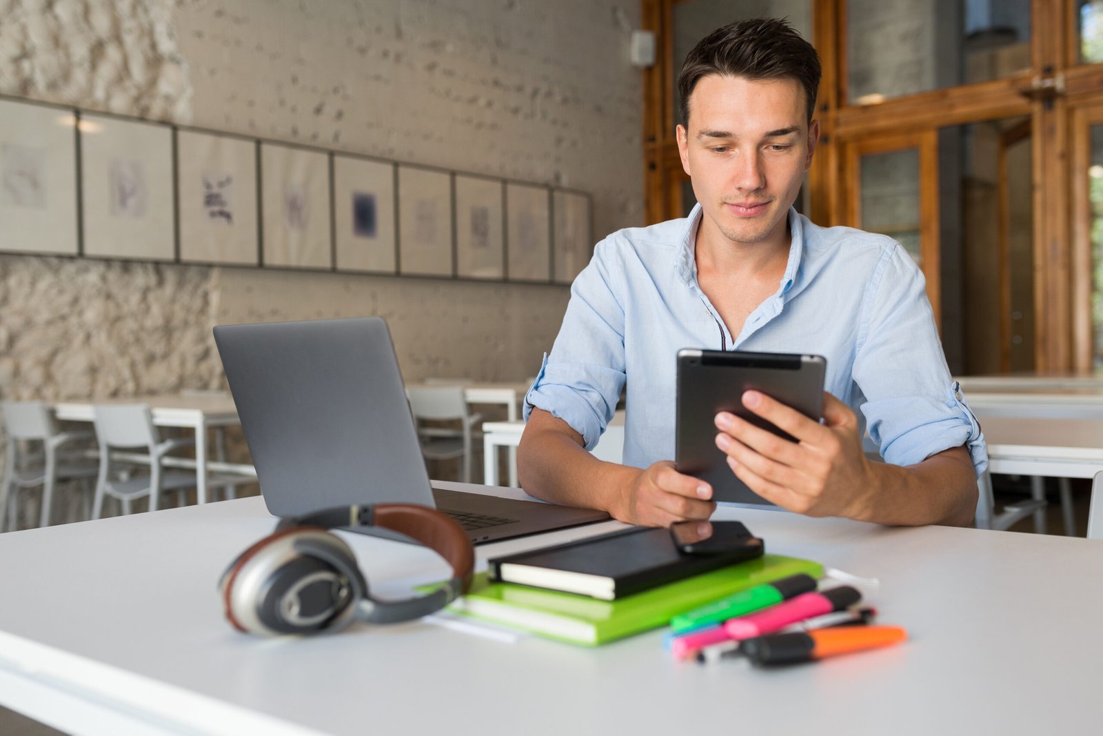 busy young hadsome busy man concentrated on work in laptop, holding tablet computer, confident andd successful